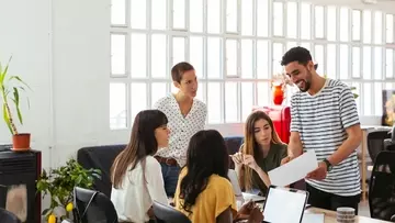 five employees around a table looking at a paper