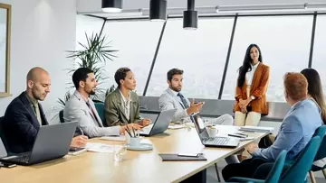 Male and female colleagues brainstorming in board room. They are at conference table in office.