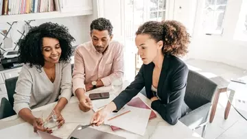 two women and one man looking over financials on a laptop.