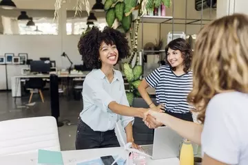 Women shaking hands over a desk