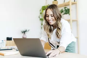 Woman standing and typing on laptop computer