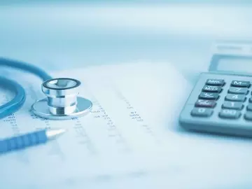 A stethoscope, pen, and calculator are laid on top of a medical chart.