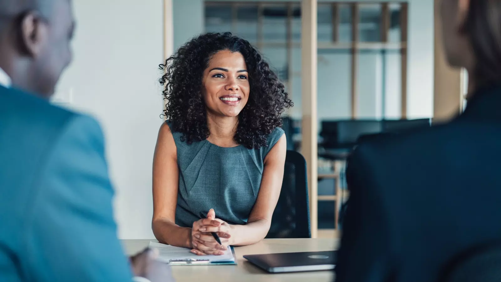 Woman sitting at a desk across from two colleagues