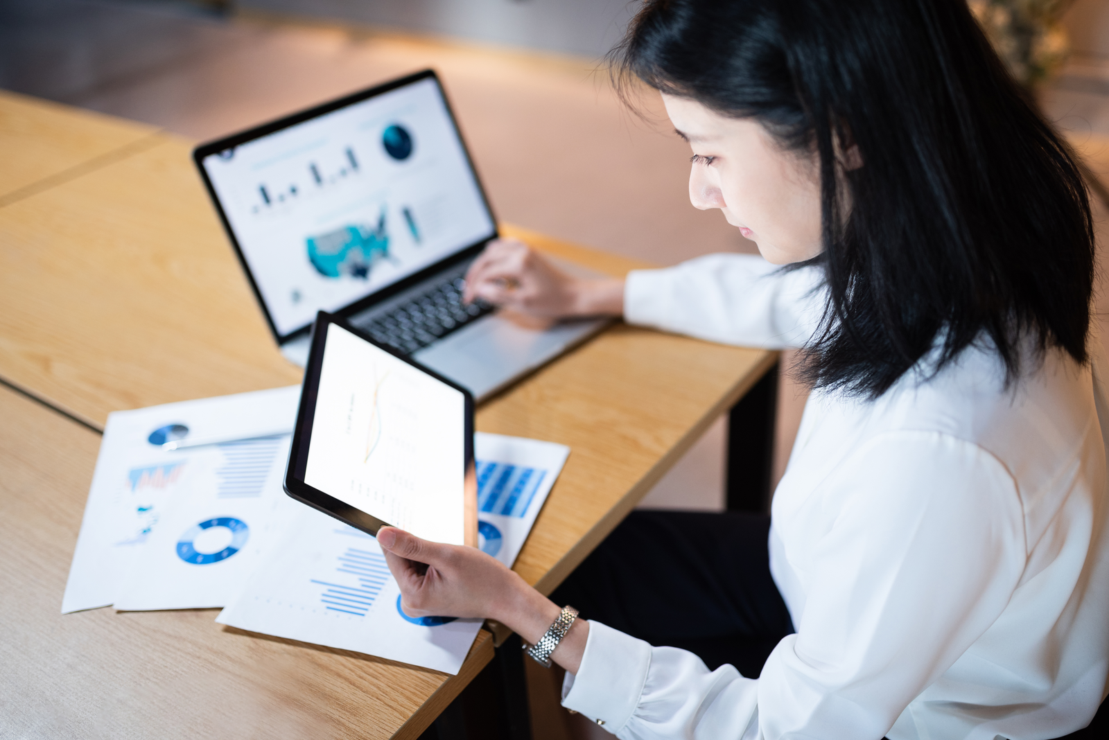 woman with tablet laptop and printed reports