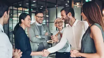 Coworkers shake hands and create a sense of belonging at work